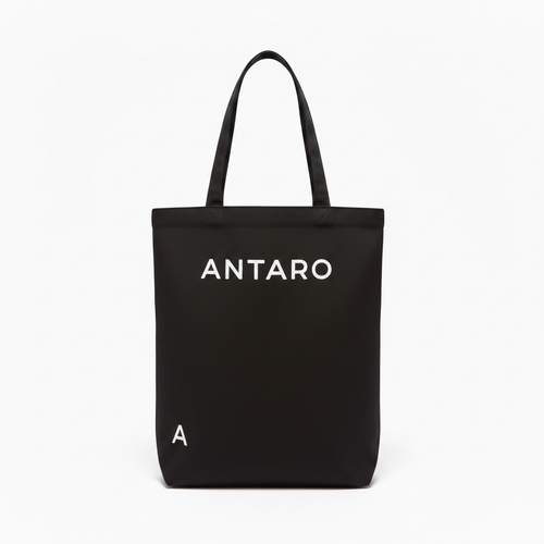 A black canvas tote bag with two top handles, featuring the brand name 'ANTARO' printed in white capital letters on the front, and a small white letter 'A' near the bottom left. The bag is photographed against a clean, solid white background.